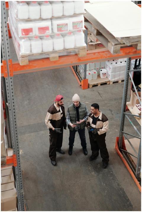 Three warehouse workers discuss logistics in an in
