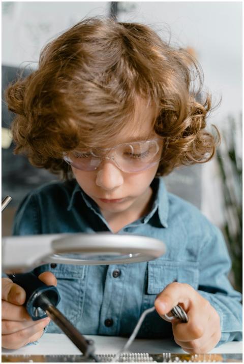 Young child with goggles exploring soldering, enha