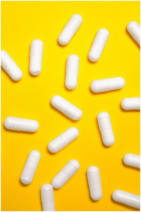 White capsules scattered on a vibrant yellow surfa