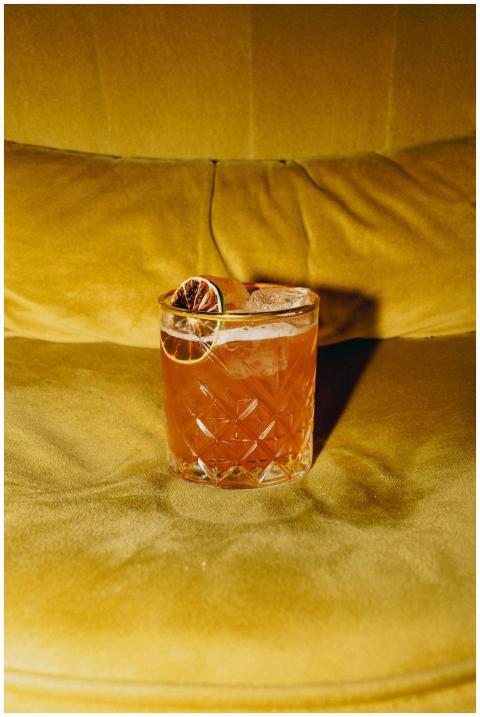 A vibrant citrus cocktail garnished with dried sli