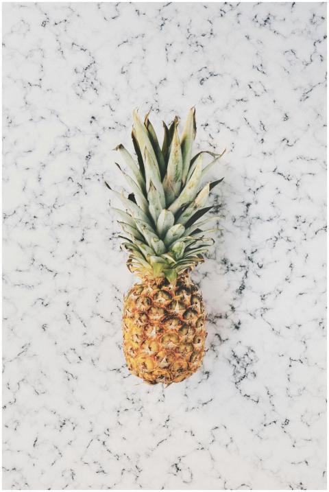 A vibrant pineapple on a minimalist marble texture