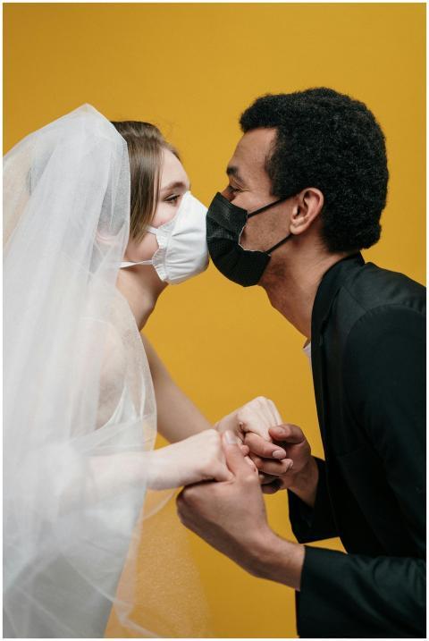 Bride and groom kissing with masks, illustrating p
