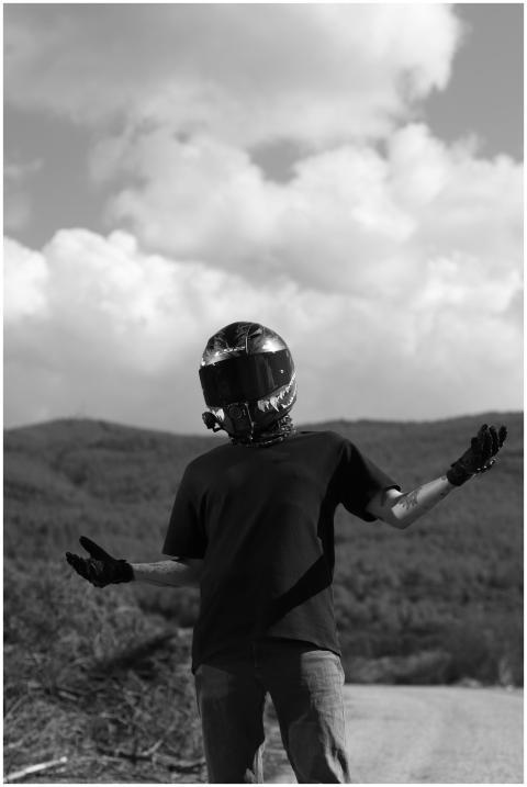 Black and white photo of a motorcyclist posing wit