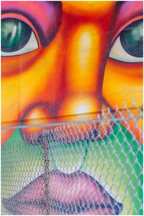 Close-up of colorful graffiti art with a chain-lin