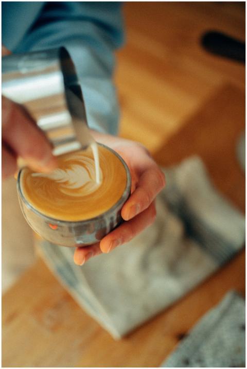Detailed view of a barista pouring milk to create
