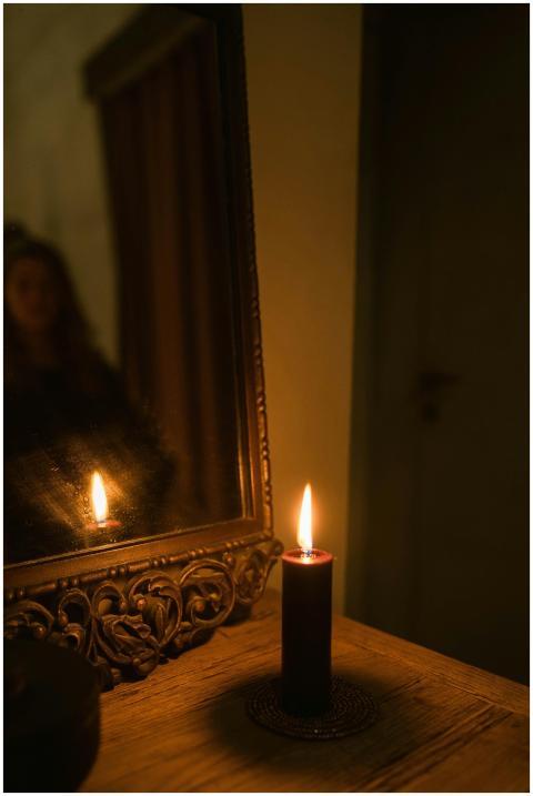 A single candle casts a warm glow, reflecting in a