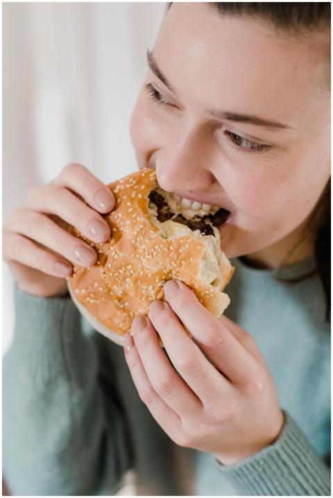 Crop female in casual wear biting tasty hamburger