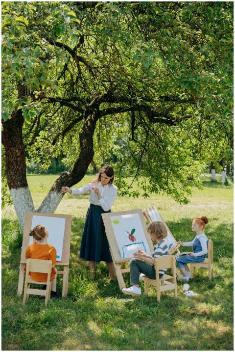 Children enjoying painting outdoors under a tree g
