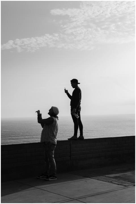 Two people with smartphones overlook the scenic oc
