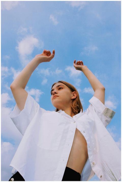 A young woman poses confidently under a vibrant bl