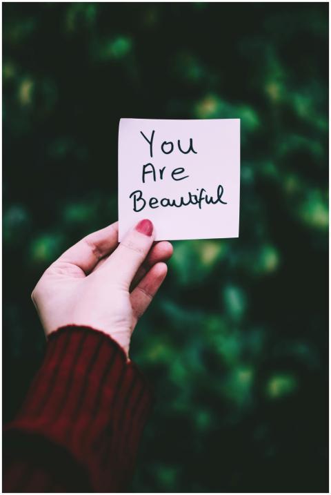 A close-up of a hand holding a 'You Are Beautiful'