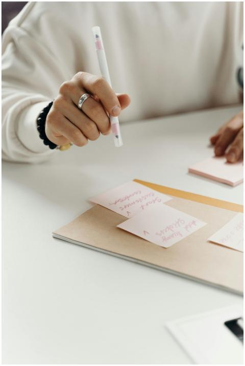 Close-up shot of a hand writing with a pen on pink
