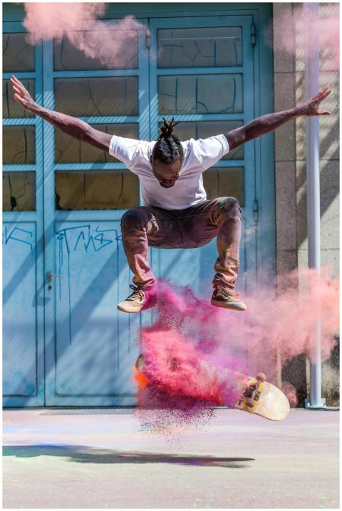Skateboarder jumps in vibrant pink powder cloud ca