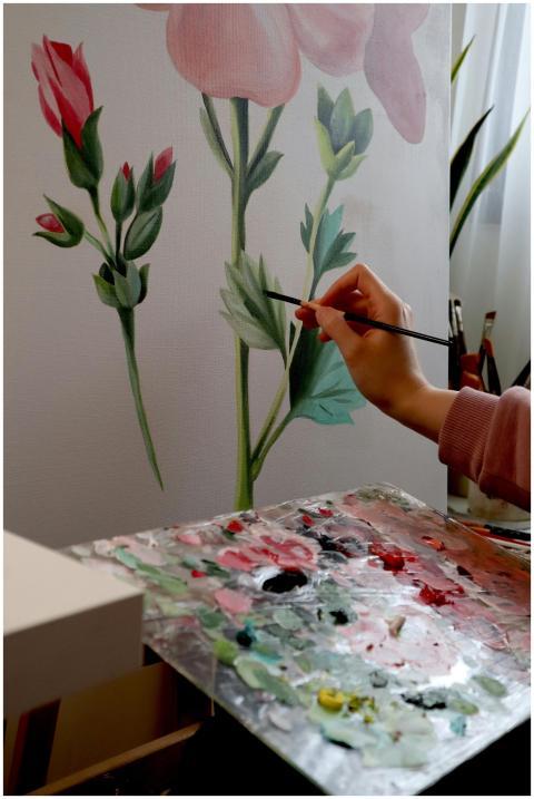 Artist painting flowers on canvas with palette, em