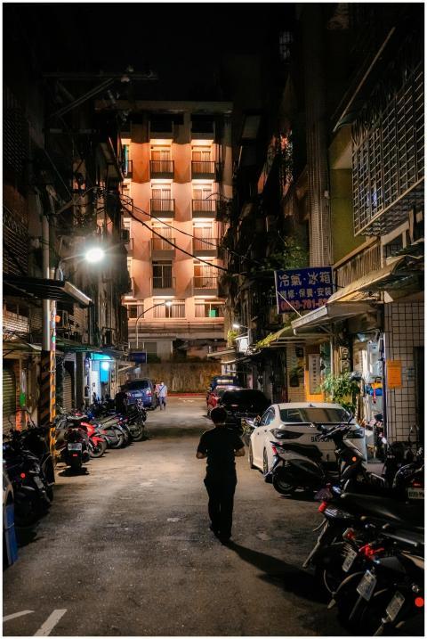 A dimly lit urban alley at night with a person wal