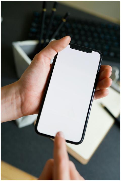 Close-up of a hand holding a smartphone with a bla