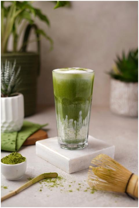 Green matcha latte in a tall glass with tools and