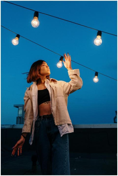 A fashionable young woman stands on a rooftop unde