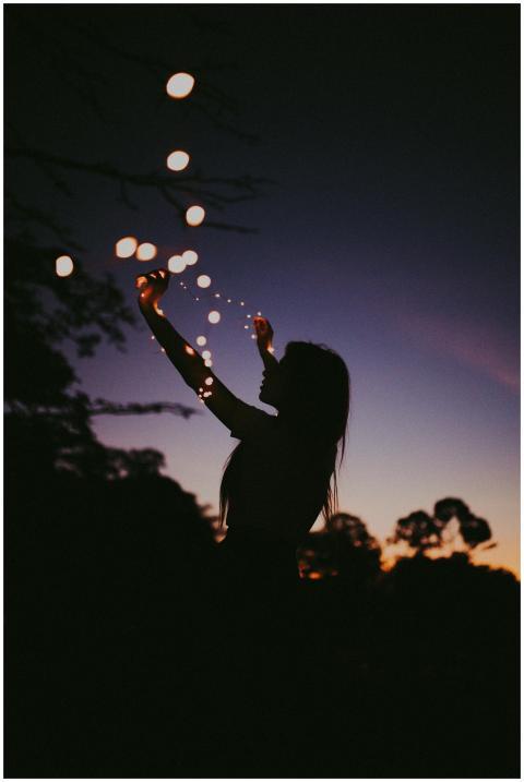 Silhouette of a woman holding fairy lights against