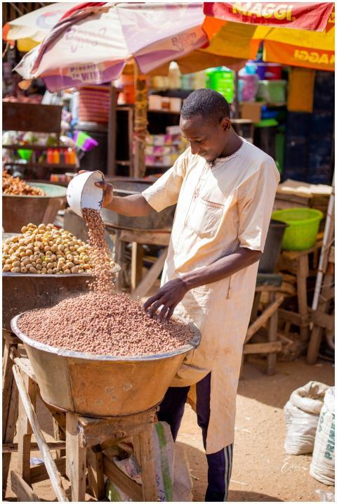 Man pouring grains in bustling market in KT, Niger