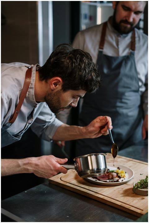 Two chefs in aprons skillfully plating a gourmet d