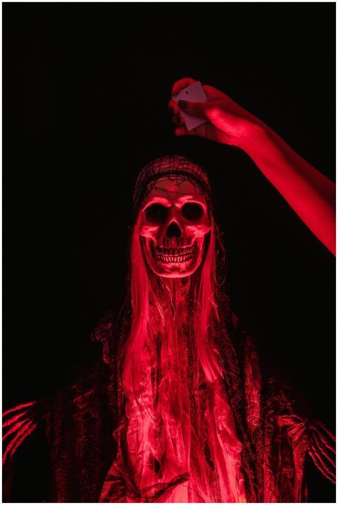 Eerie red-illuminated skeleton with human hand, pe