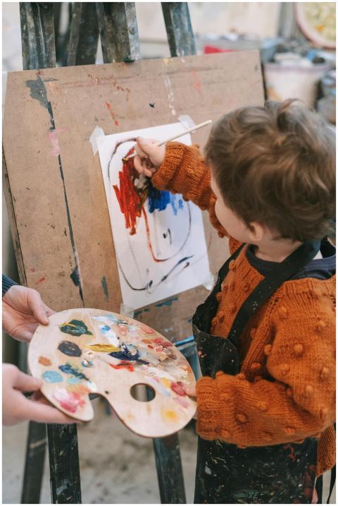Child painting on an easel with colorful paints, c