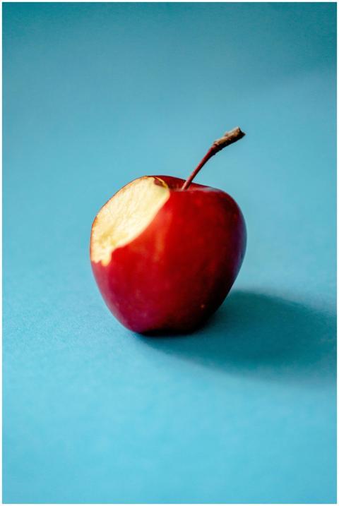 A fresh red apple with a bite taken out against a