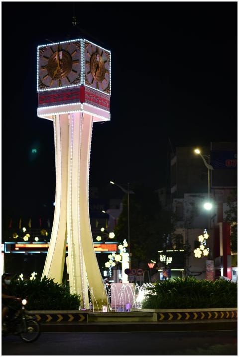 Brightly lit clock tower surrounded by city lights