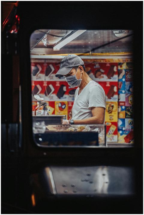 A food truck vendor wearing a face mask prepares f