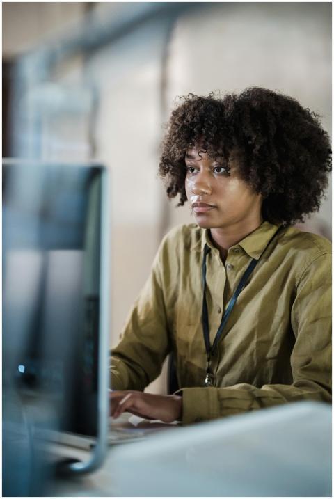 Focused young woman working at a computer in an of