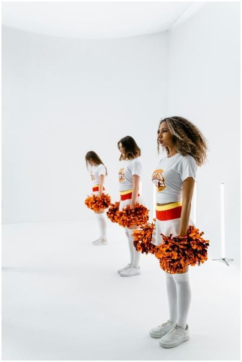 Three female cheerleaders in formation holding ora