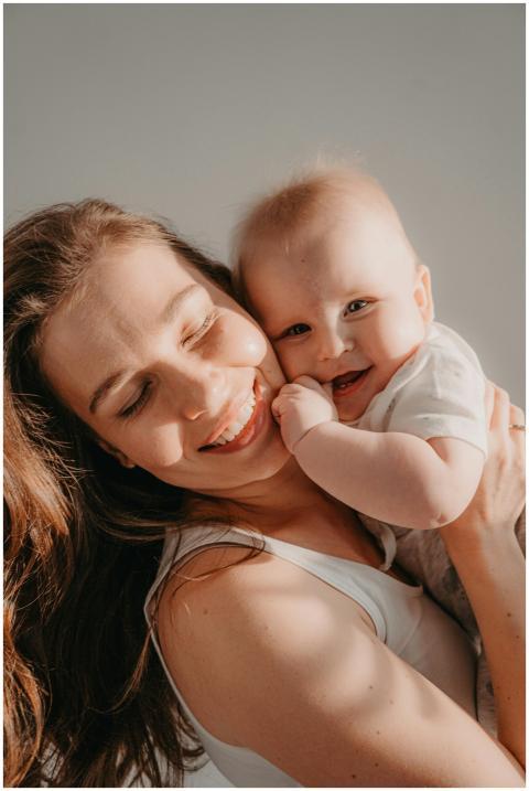 A joyful mother lovingly hugs her smiling baby, bo