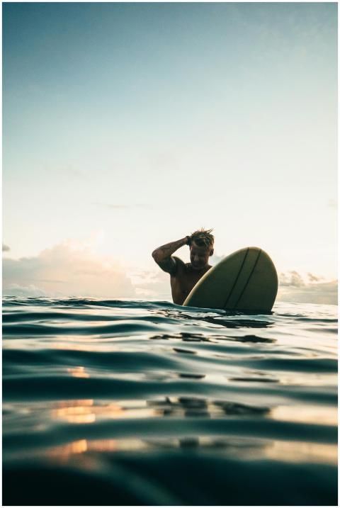 A surfer enjoys the serene waters and a stunning s