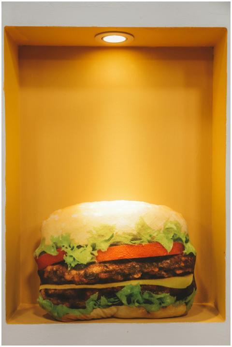 A realistic burger sculpture lit within an indoor