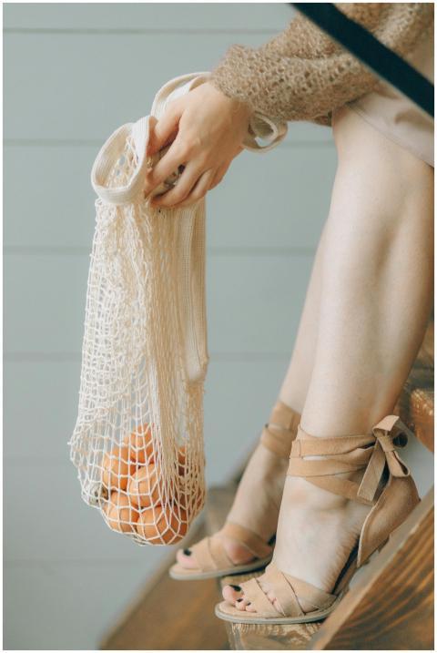 Elegant woman sitting on stairs holding a mesh bag