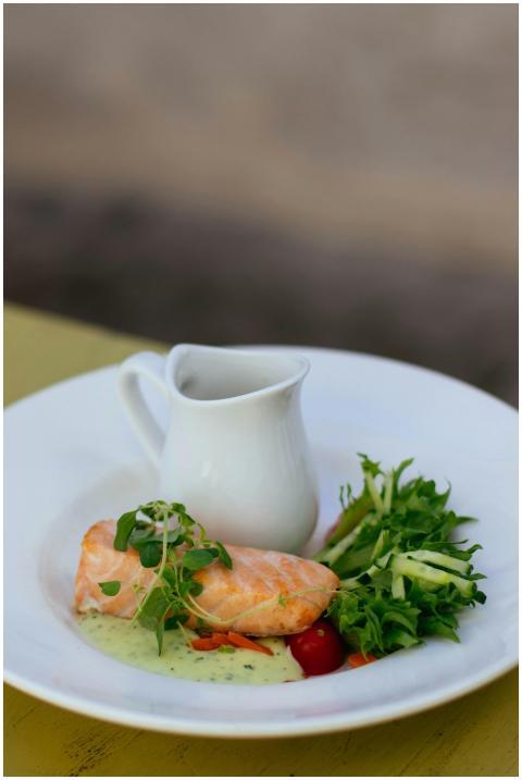 Gourmet salmon dish with greens and sauce on a whi