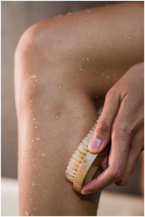 Close-up of a hand using a body brush on a wet leg