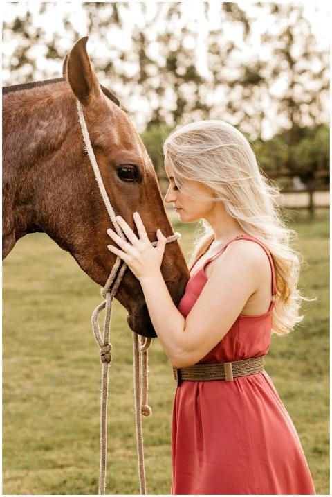 A woman in a red dress gently embracing a horse in