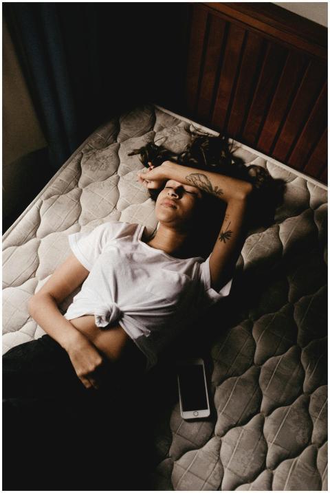 A woman in a white shirt lying on a bed inside a d
