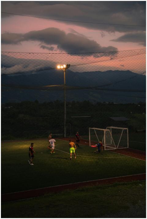 Players enjoy a soccer game at dusk under bright s