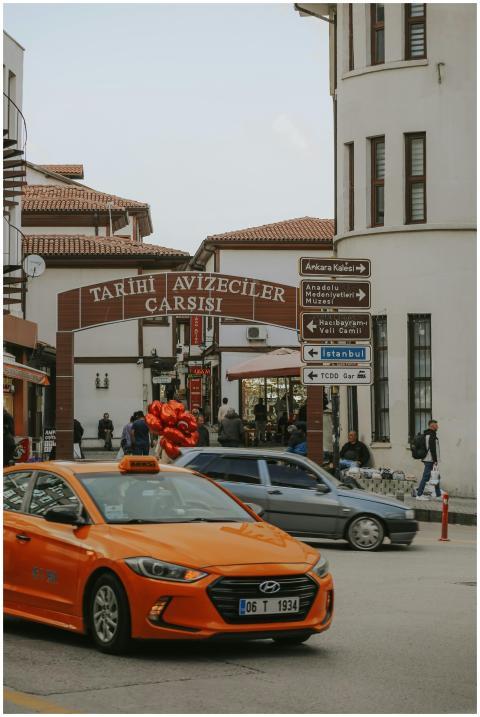 Orange taxi driving by Tarihi Avizeciler Carsisi e