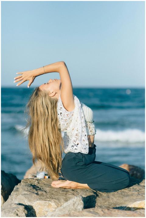 Serene woman in yoga pose on a rocky beach during