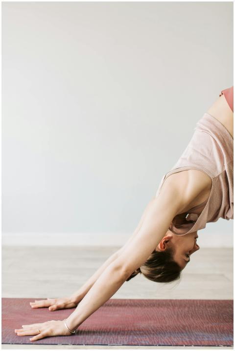 Young woman in downward dog position on yoga mat,