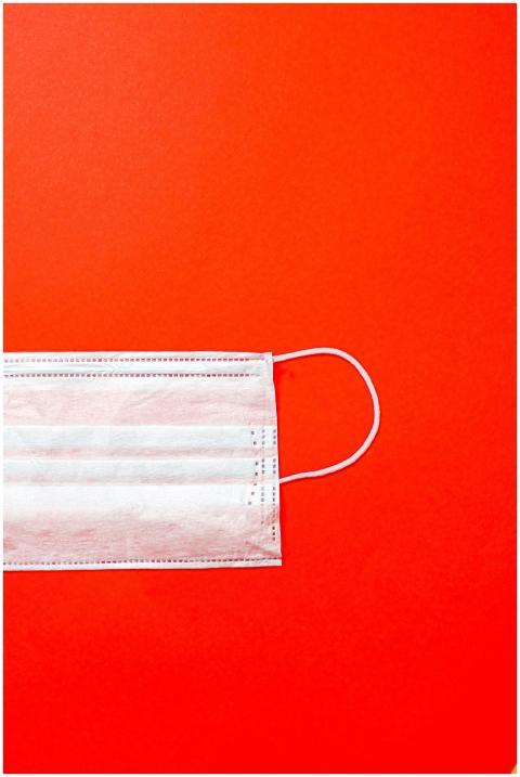 Close-up of a surgical mask on a vibrant red backg