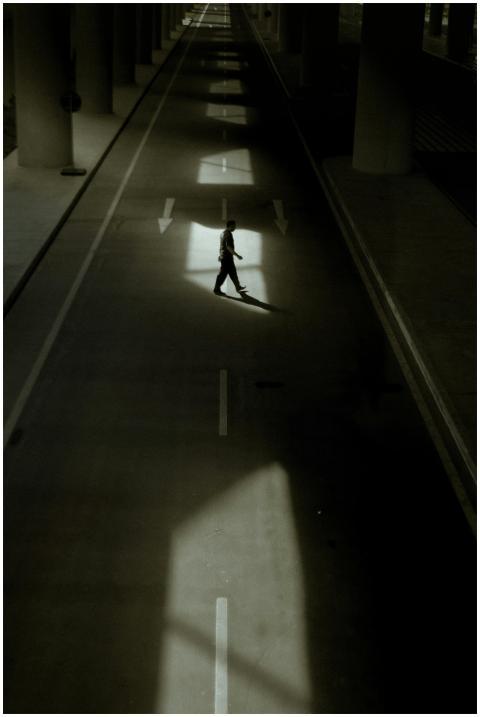 A person walks alone on a shadowed city street und