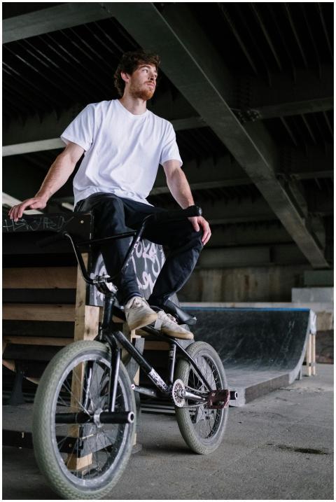 BMX cyclist sitting on a bike under a bridge, wear