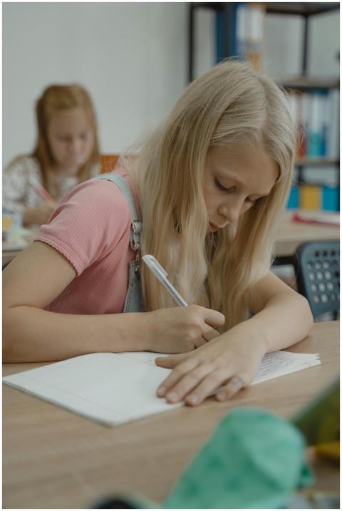 Blonde girl attentively taking notes in a classroo