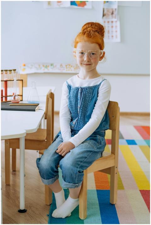 Child in classroom setting wearing safety glasses,