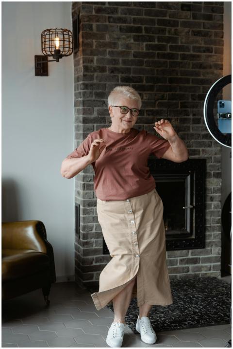 A cheerful senior woman dancing in a cozy living r